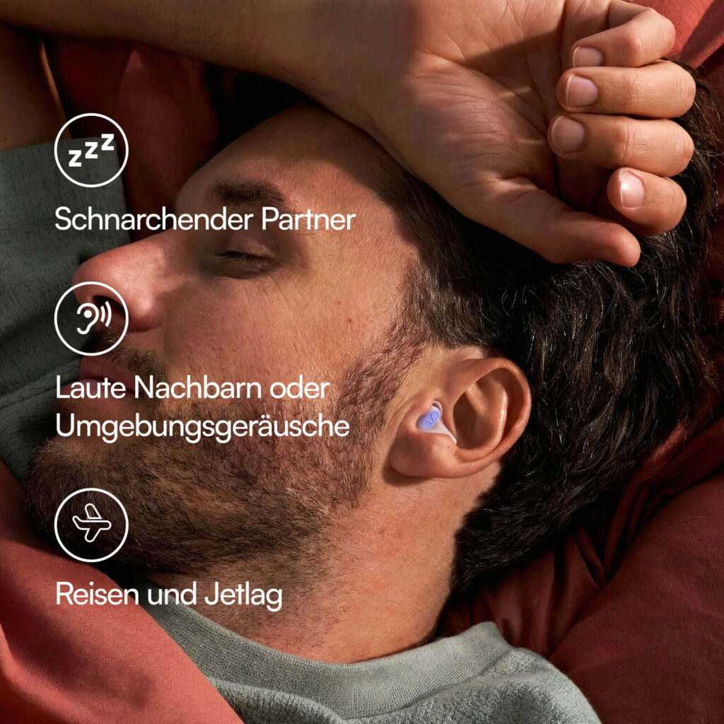 Mann schläft mit violetten Ohrstöpseln gegen Schnarchen und Umgebungsgeräusche