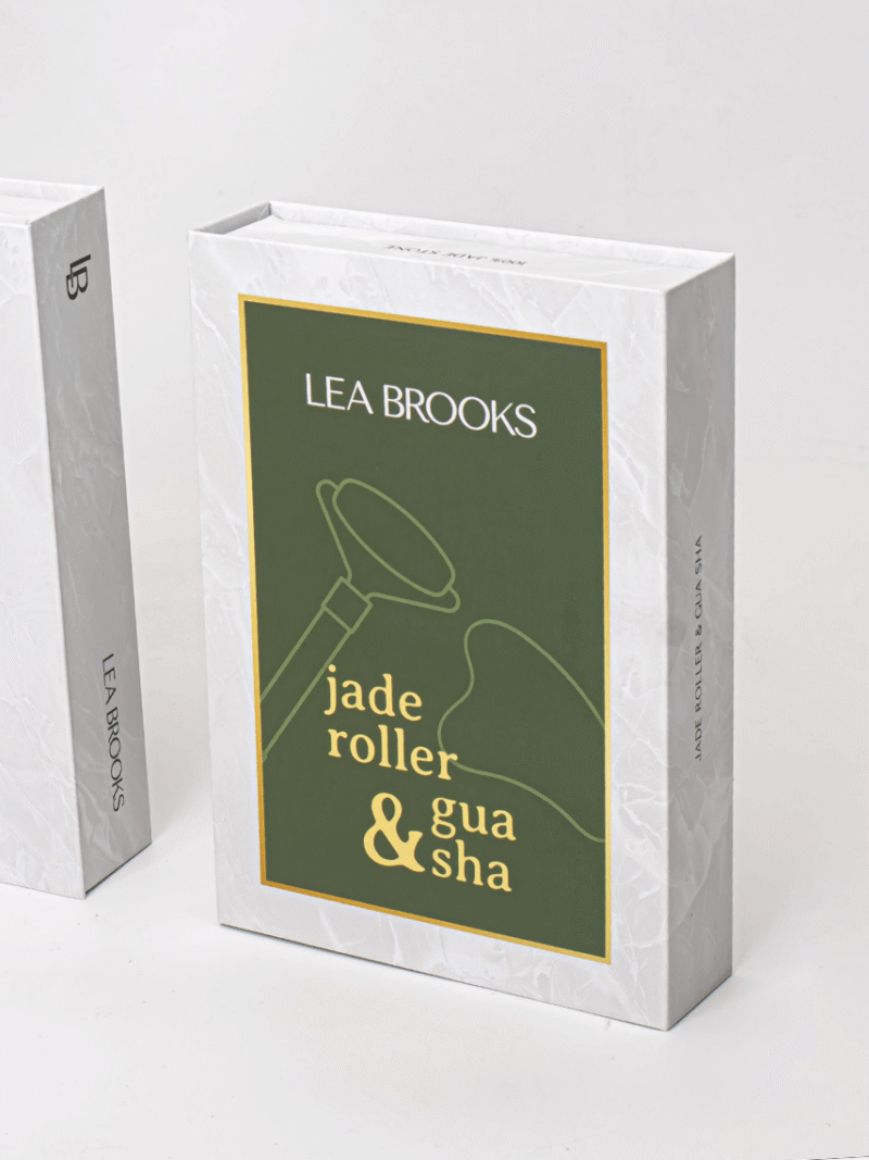 Verpackung des Lea Brooks Jade-Rollers und Gua Sha, weiße Marmorbox mit grünem Etikett und goldener Schrift