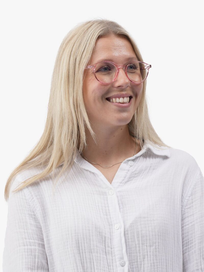 Porträt einer lächelnden blonden Frau mit transparent rosafarbener runder Brille und weißem Hemd