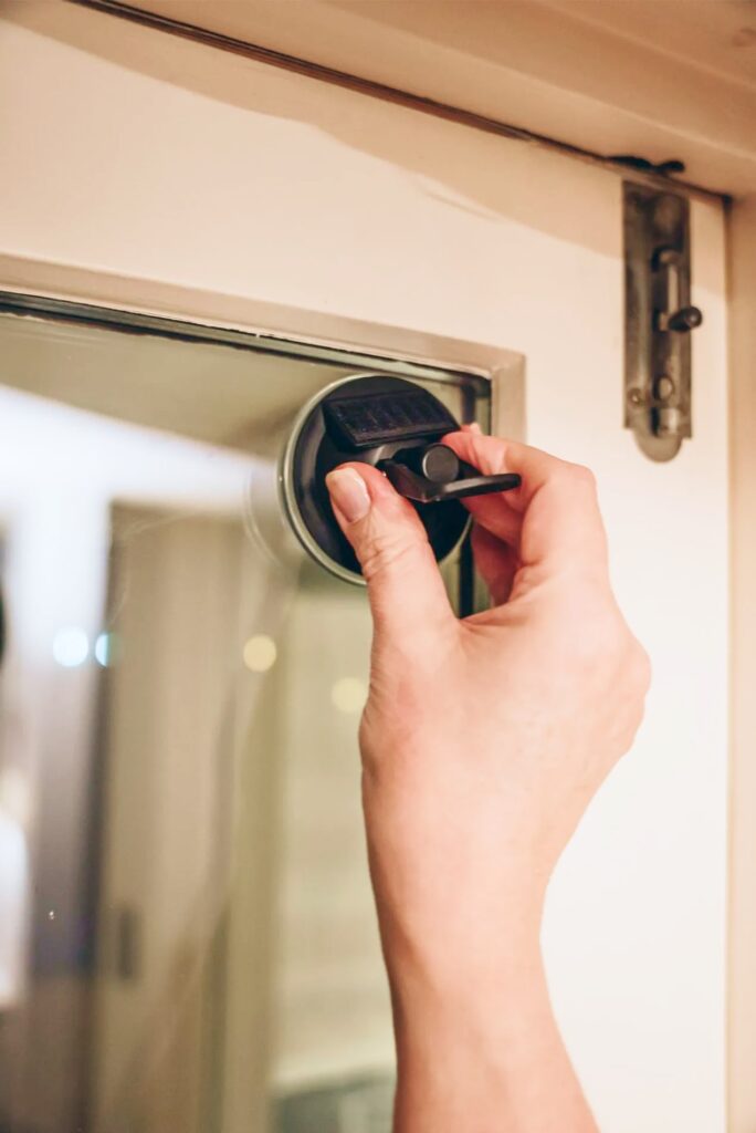 Hand befestigt schwarzen Saugnapfgriff an Glasscheibe nahe Fensterrahmen